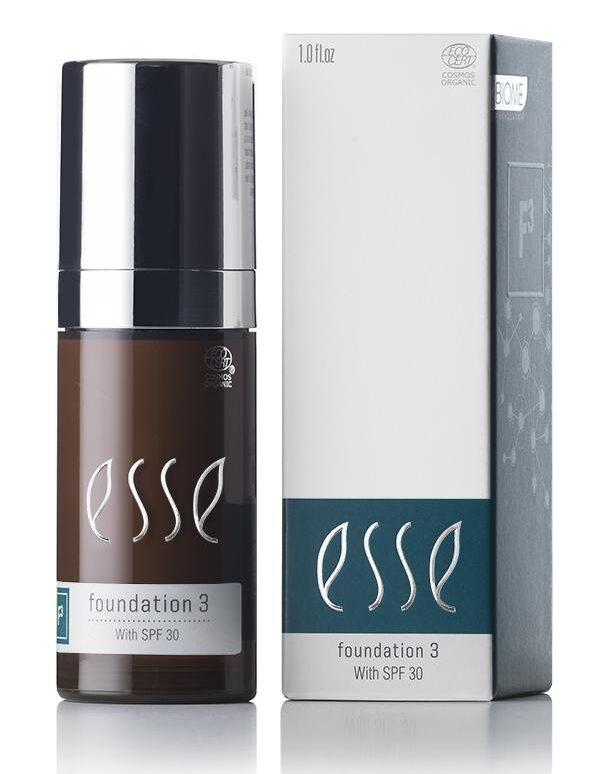 A sleek pump bottle and matching box of Esse Foundation with SPF 30 are displayed side by side. The brown bottle features a silver top, while the box is white with blue accents showcasing the product name and details.