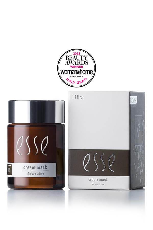 Image of the Award-Winning Esse Cream Mask, a skincare product in a brown jar with a silver cap, placed next to its white and grey box packaging. An award seal above proudly displays "Beauty Awards Winner 2023" by Woman & Home South Africa with "Holy Grail" mentioned below.