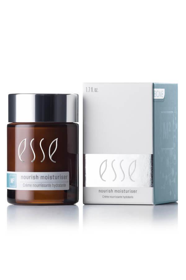 A brown glass jar of Esse Nourish Moisturiser is displayed next to its silver and white rectangular box. The jar has a silver lid and features the product name and details in white and blue text. The box showcases similar branding and text.