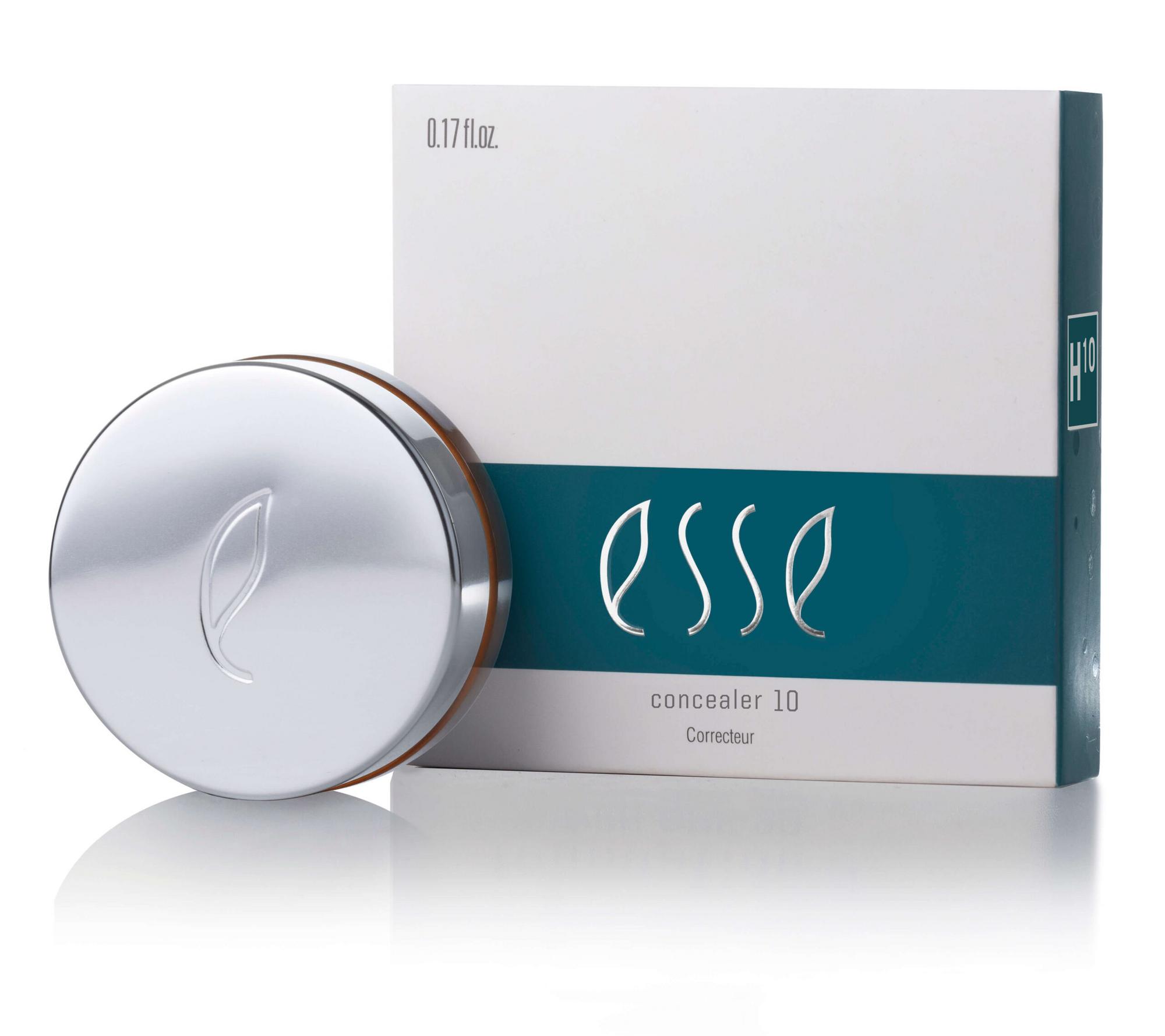 A round, silver compact container featuring a minimalist leaf logo is placed in front of its matching box. The box also displays the same leaf logo and is labeled "Esse Concealer 10" with text indicating "0.17 fl. oz." and featuring a teal band across the middle.